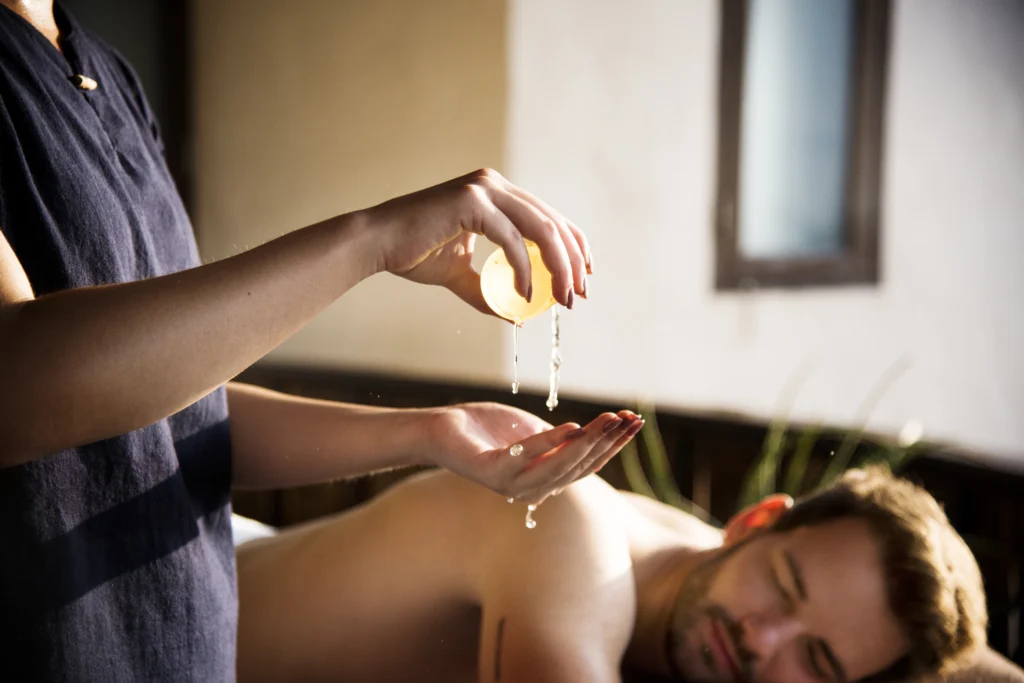a massage therapist using essential oil to enhance massage