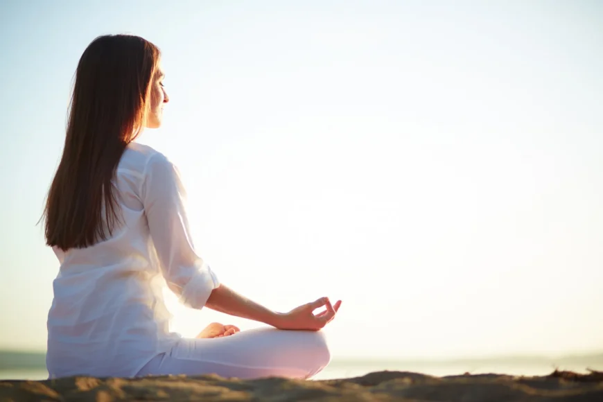 woman sitting in yoga pose for meditation during sunrise