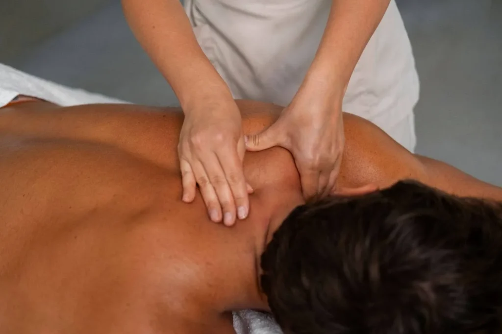 A man getting an intense deep tissue massage therapy around his neck in a spa