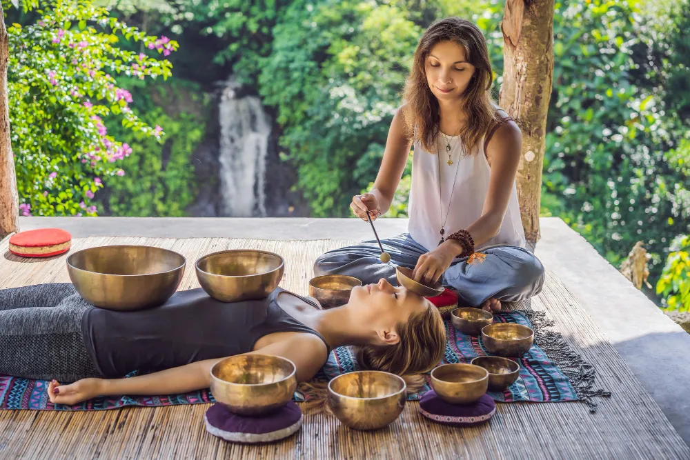 A young woman doing meditation while using a chanting bowl popular in Buddhist traditions