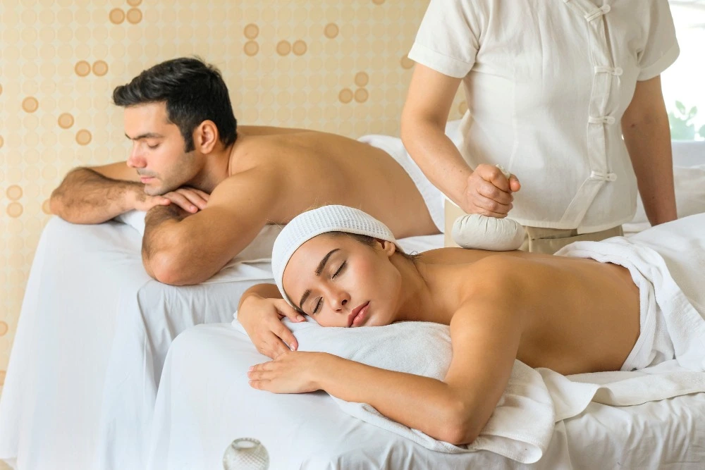 A couple enjoying herbal pressure massage in a spa
